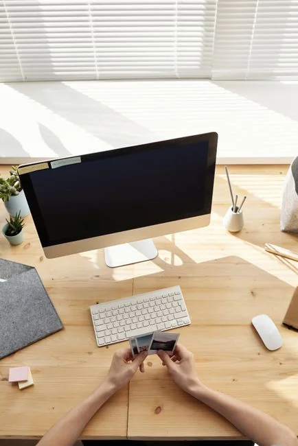 A photographer working at a creative setup with a laptop and Wacom tablet, focused on editing photos indoors.